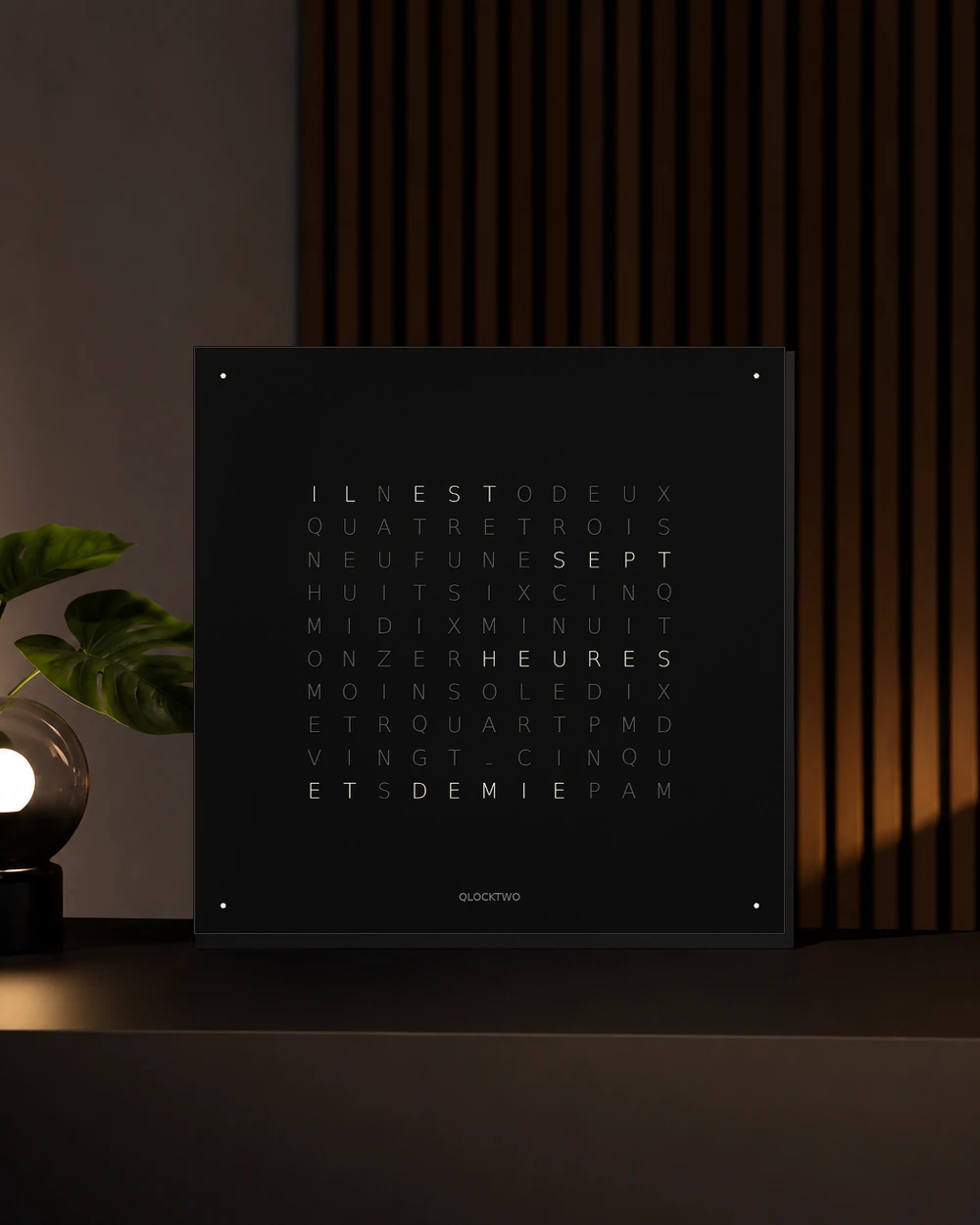 Horloge carrée noire affichant l’heure en toutes lettres françaises dans un salon contemporain