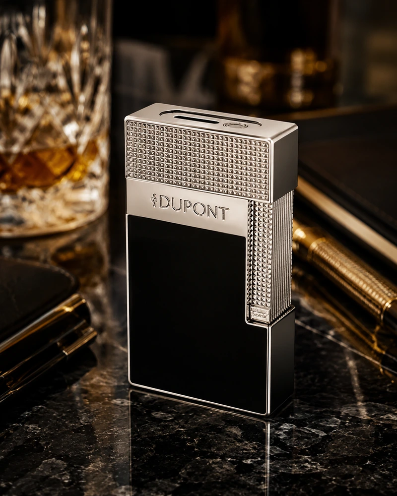 Briquet chrome et laque noire posé sur un marbre sombre dans une ambiance de bureau